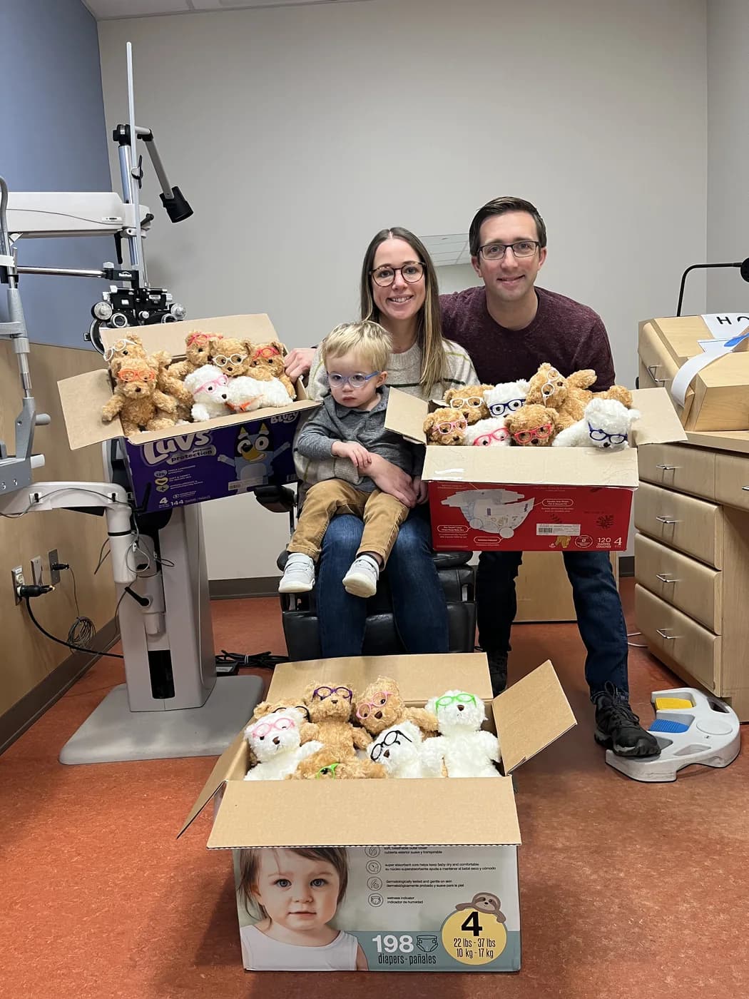 Kirsten, Jeff, and Roy Pipp with boxes of donated teddy bears at the ophthalmology clinic at Helen DeVos Children's Hospital