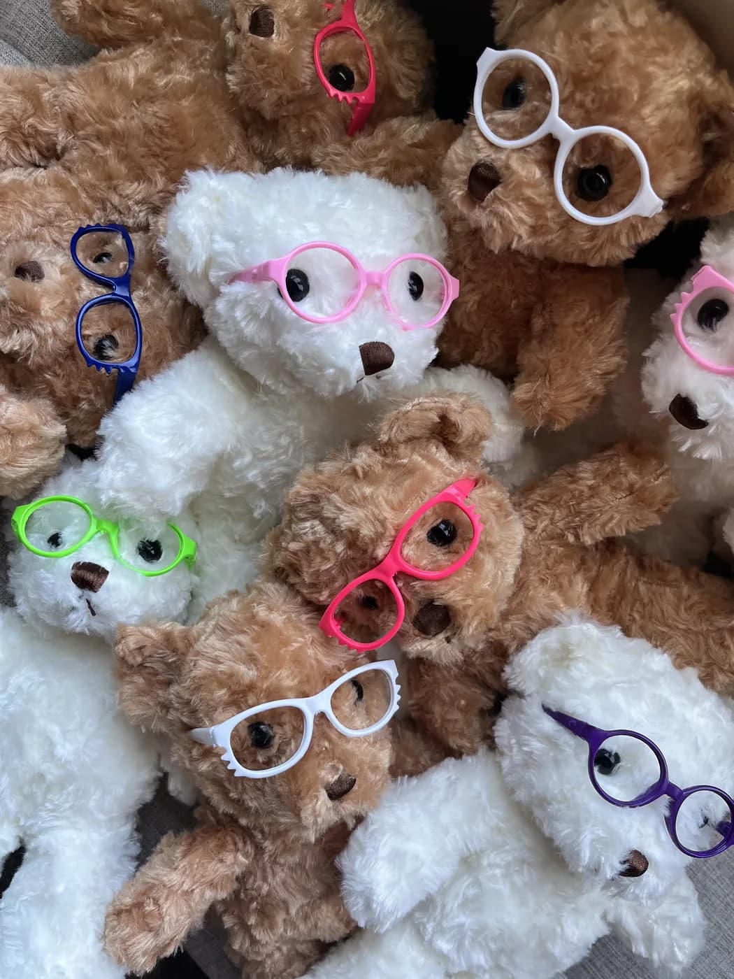 Donation teddy bears wearing hand-sewn glasses in a range of colors