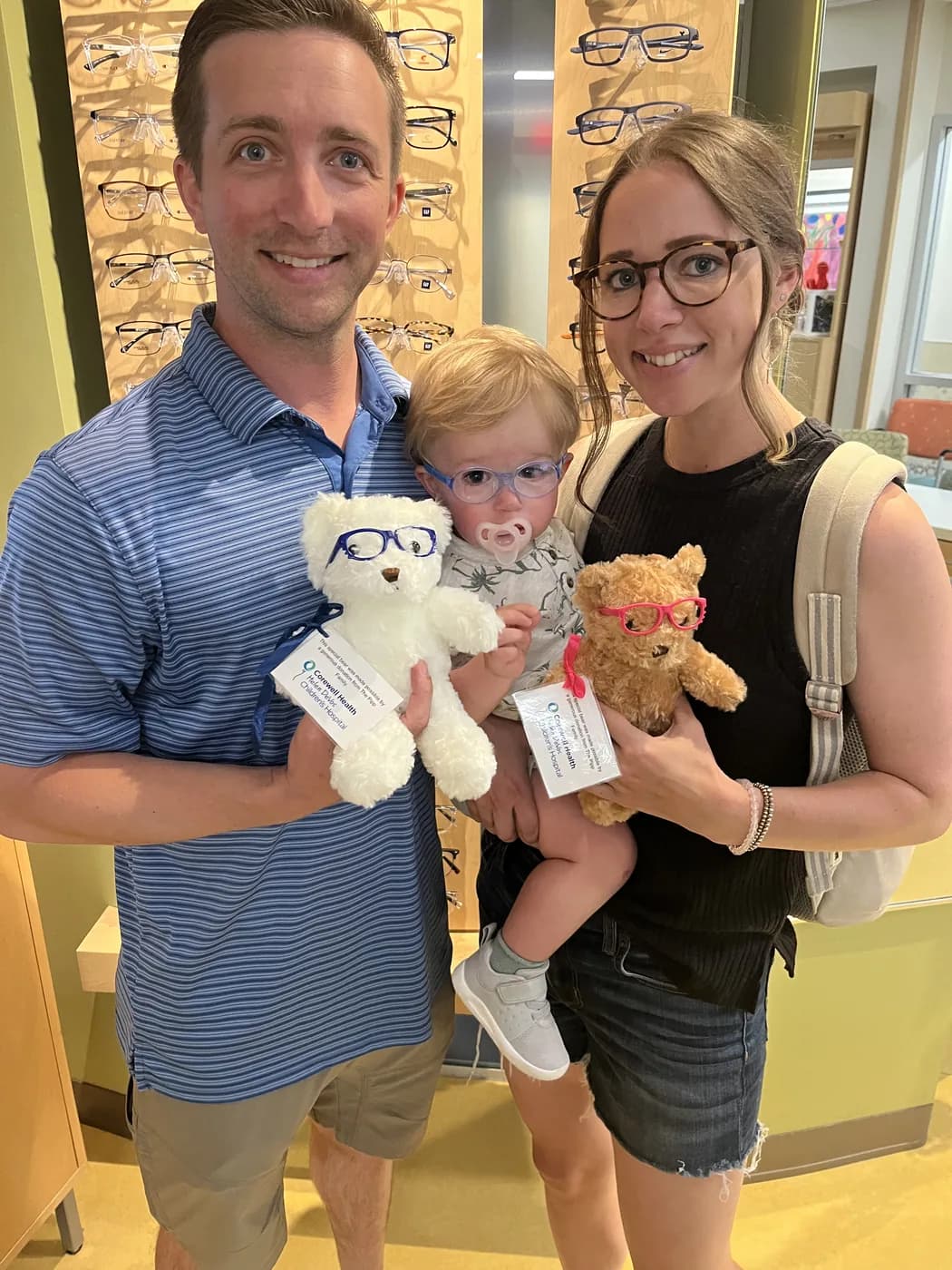 Kirsten and Jeff Pipp with Roy, holding donation bears at the optical clinic